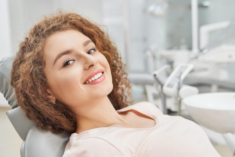 Confident woman smiling in a dental clinic, representing dental veneers in Curaçao.