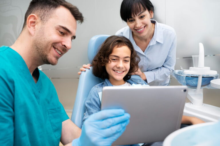 A trusted dentist in Curaçao showing a young patient and her mother dental results on a tablet, reflecting friendly, family-centered care at Klinika Dental Sta Rosa