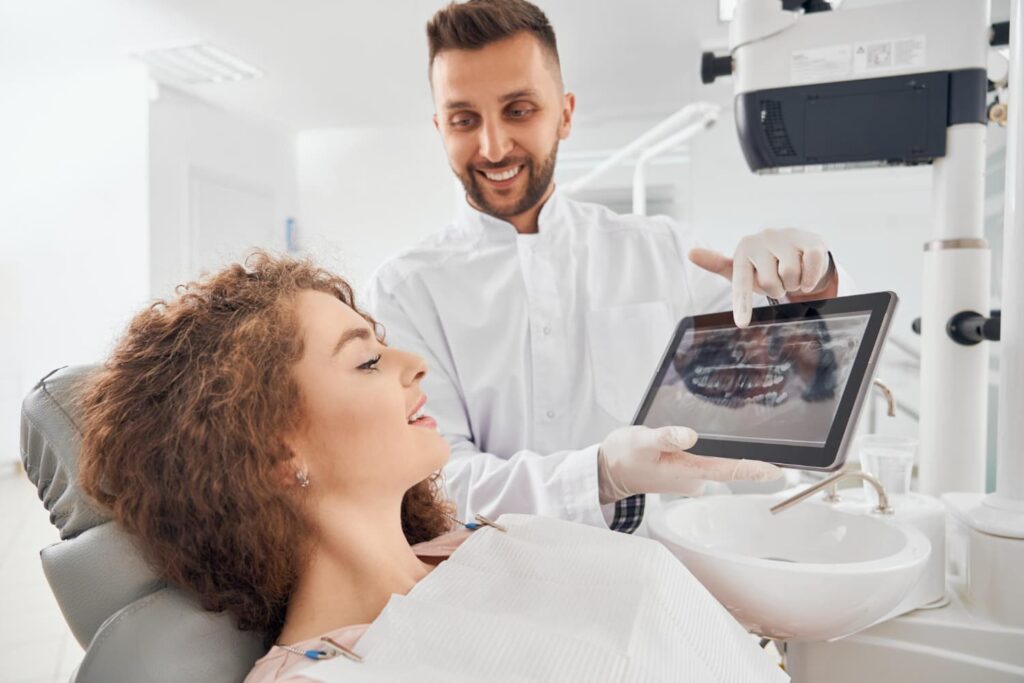 Dentist explaining dental X-ray to a patient during a consultation - Dentist vs. Orthodontist