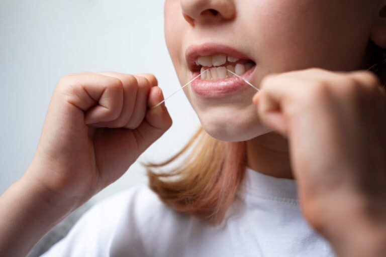 Person flossing between teeth to prevent cavities and gum disease