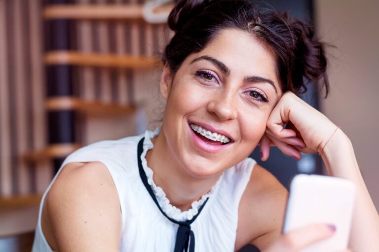 Smiling woman with adult braces using her mobile phone
